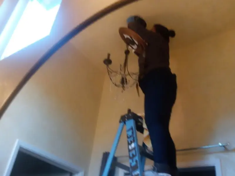 Electrician installing a chandelier in a Marbletown residence